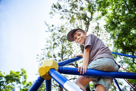 Young boy climbing spiderweb playground equipment at park