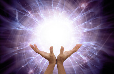 Bio energy healer sending vortex energy - female open cupped hands with a radiating ball of white energy above against a spiraling purple ethereal energy field background and copy space
