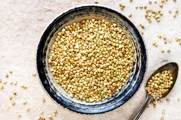 Hulled buckwheat grains in a rustic bowl against light stone background