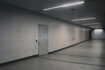 Obraz premium Empty concrete hallway with single locked door with ‘G’ on the front.