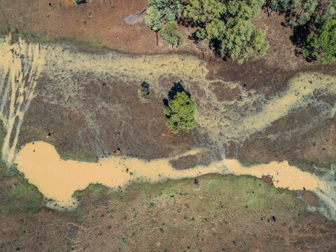 Full creek and overflowing dam in rural paddock