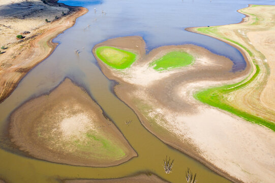 Aerial view of a dirty river winding around small islands with patches of grass