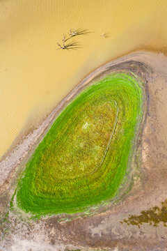 Looking down on patch of green land next to a muddy river