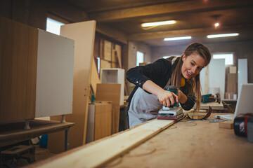 Fototapeta premium Female Carpenter Using Electric Sander in a Woodworking Workshop Setting