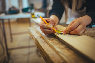 Close-Up of Hands Using Measuring Tape and Pencil on Wooden Surface