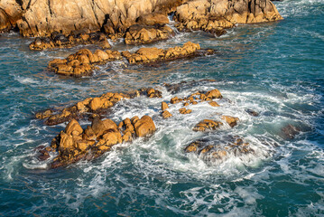 Coastline rock formations at sunrise with a swirling waves braking against the rocks