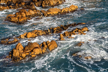 Coastline rock formations at sunrise with a swirling waves braking against the rocks