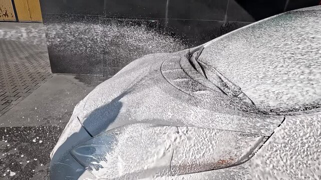 General cleaning of the car. Washing the car at a contactless car wash with foam and water under high pressure. Slow motion.