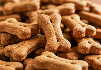 Fototapeta premium Pile of crunchy bone-shaped dog biscuits for pet treats and snacking, National Pet Day