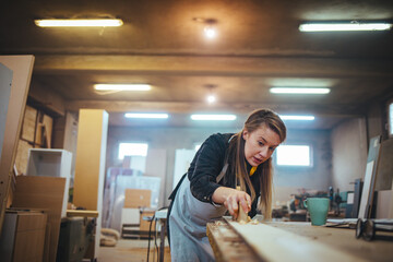 Fototapeta premium Focused Female Artisan Working in a Woodworking Workshop on a Project