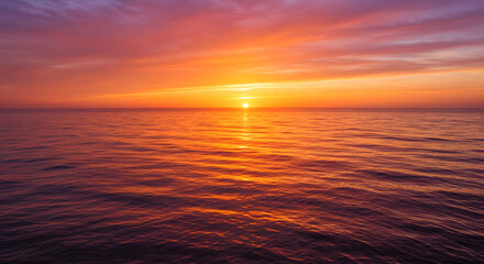 Obraz premium A stunning sunset over the ocean, with warm orange and pink hues reflecting on the water.