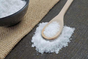 Sea salt in a wooden spoon on the stone table. Sea salt is used for seasoning, preserving food and making beauty treatment the scrub with salt.