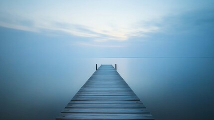 Obraz premium Serene Wooden Pier Extending into Calm Waters Under Soft Blue Sky at Dusk