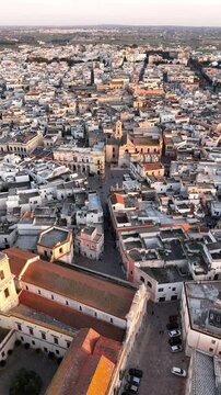 Aerial drone view of Nardo, a historic town in southern Italy, bathed in golden sunset light. The old towns dense architecture, whitewashed buildings, and narrow streets highlight its rich cultural