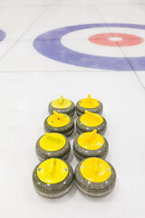 Set of curling stones for one team, placed near concentric rings on an ice rink
