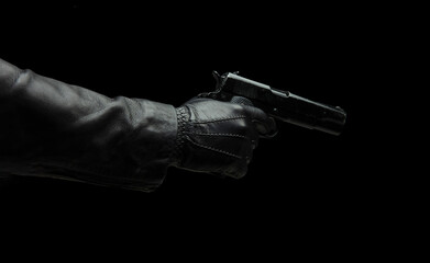 Gun on dark background, closeup, gloved hand holding a pistol. Crime, murder