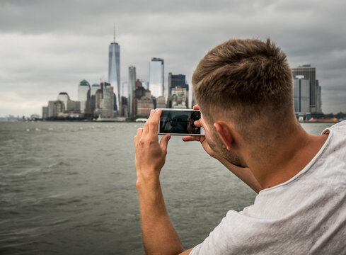 tourist photograph with his smartphone the New York City skyline from Hudson River