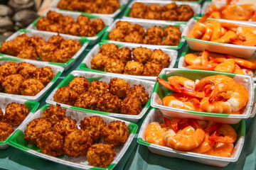 Japanese seafood snacks at a fish market, featuring deep-fried seafood balls and boiled shrimp neatly arranged in takeaway trays
