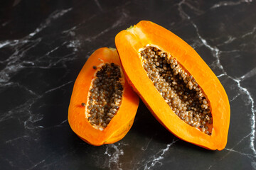 A freshly ripped papaya, vibrant orange, oozing sweet nectar, with torn skin revealing juicy flesh and scattered black seeds inside.
