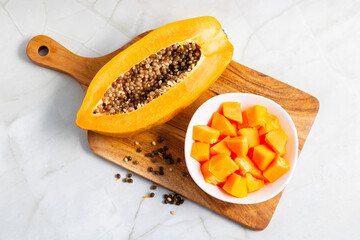 A freshly ripped papaya, vibrant orange, oozing sweet nectar, with torn skin revealing juicy flesh and scattered black seeds inside.