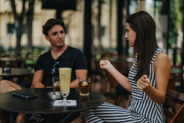A young couple enjoys drinks while having a lively interaction at an outdoor cafe. The casual setting enhances their connection and communication in a relaxed atmosphere.