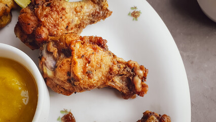 crispy and roasted chicken thigh on white plate with sauce and gray background