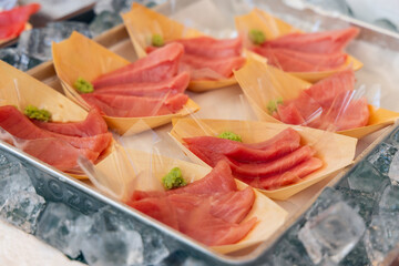 Thinly sliced tuna sashimi is served in wooden trays with wasabi displayed on crushed ice at a seafood market in Tokyo ready for immediate tasting