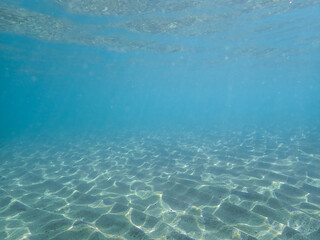 Dark blue ocean surface seen from underwater. Abstract waves underwater and rays of sunlight...