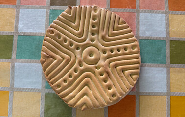 Traditional sardinian sa pintadera bread resting on colorful tablecloth