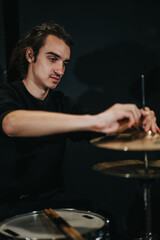 A focused drummer fine-tuning his drum kit during a band rehearsal in a studio. Captures the artistic process and preparation involved in creating music for a live concert or performance.