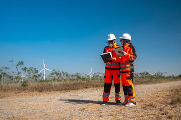 Male and female wind turbine engineers working together outdoor wind turbine field