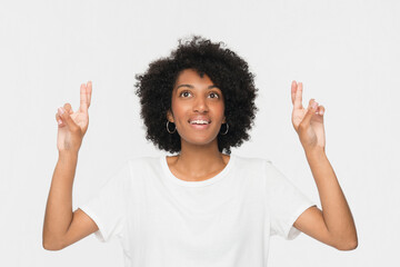 Hopeful happy young African American girl woman female student crossing fingers hoping for good...