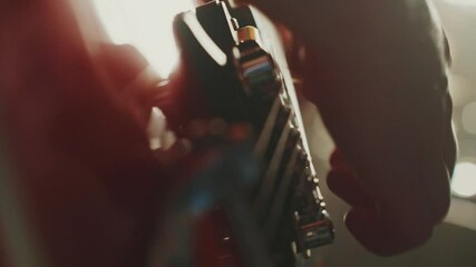 Close up of a guitarist tuning the strings of his electric guitar, adjusting the tuning pegs with precision and care, preparing for a music session or live performance