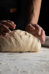 Male hands making dough for pizza, bread, pasta. Cooking bread. Kneading the Dough. Isolated on dark background. Copy space, production of flour products