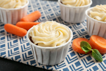 Delicious carrot muffins with fresh vegetables on black table, closeup