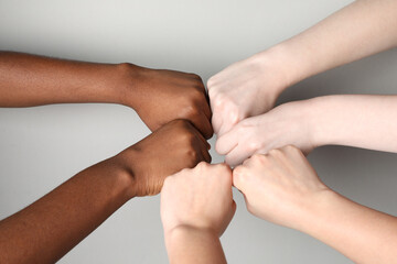 Fototapeta premium Stop racism. People of different skin colors bumping fists on light grey background, closeup