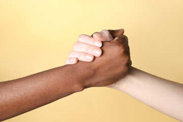 Stop racism. People of different skin colors holding hands on beige background, closeup