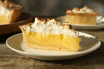 Piece of delicious pie with browned meringue on wooden table, closeup