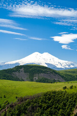 Fototapeta premium snowy mountain peaks on a background of green hills