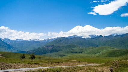 snowy mountain peaks on a background of green hills