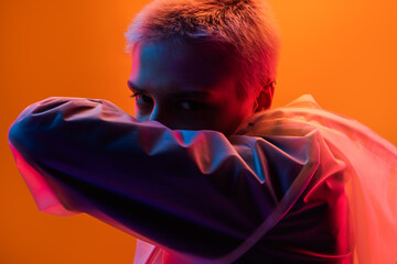 Creative portrait featuring a woman in vibrant neon lighting with futuristic undertones. The orange...