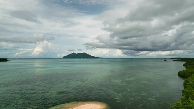 Aerial view of tropical beach and serene ocean with moody clouds and vibrant reef, Port Vila, Shefa, Vanuatu.