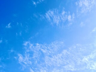 The sky is bright blue with thin white clouds. The sun is shining brightly.