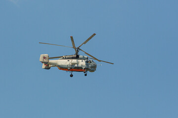 Flying helicopter against the blue sky. Air transport. The helicopter flies in the cloudy sky. Light color Rotorcraft.