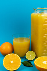 Orange pillows, a glass of orange juice on a blue background. Oranges and juice