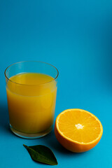 Glass of orange juice in glass close-up. Cut oranges on the table.