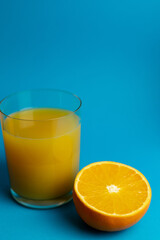 Glass of orange juice in glass close-up. Cut oranges on the table.