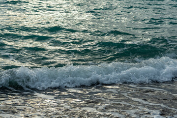Splash of sea waves crashing on a pebble beach. Warm summer evening on the Black Sea coast