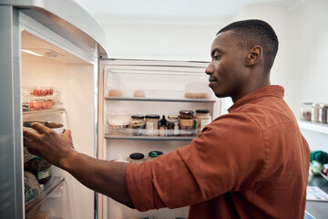 Young African man looking for something in his refrigerator