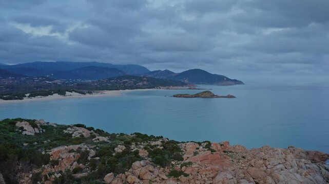 Aerial view of Capo Spartivento and Spiaggia di Cala Cipolla with a cloudy sky at dusk, Domus de Maria, Sardinia, Italy.